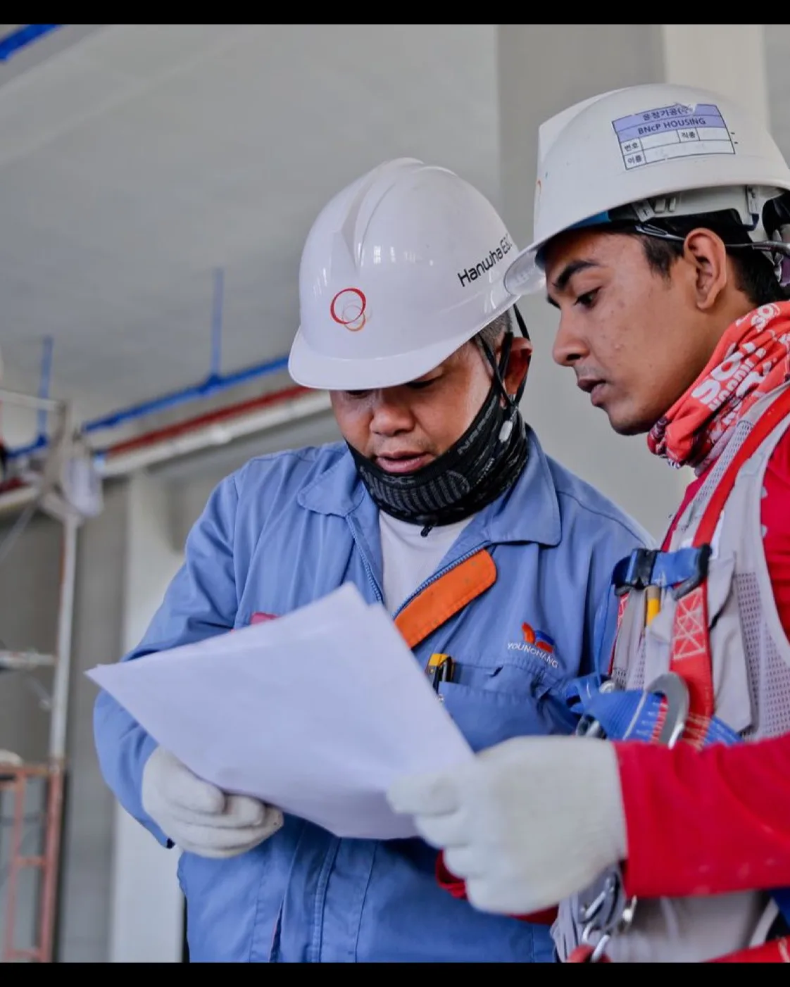 Deux travailleurs consultant un plan sur un chantier